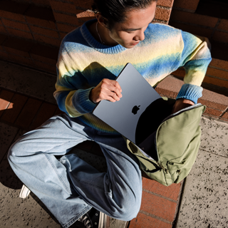Vista frontal de una persona guardando un MacBook Air de 15 pulgadas cerrado en una mochila