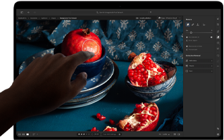 MacBook Pro con pantalla PROLED XDR con una imagen con frutas, cuencos de cerámica y tejidos azules, una mano se acerca a la pantalla para interactuar con la obra de arte